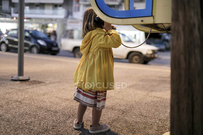 Back view of little girl using telephone booth — Stock Photo