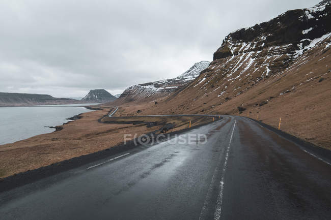 Исландия, пустая мокрая прибрежная дорога — стоковое фото