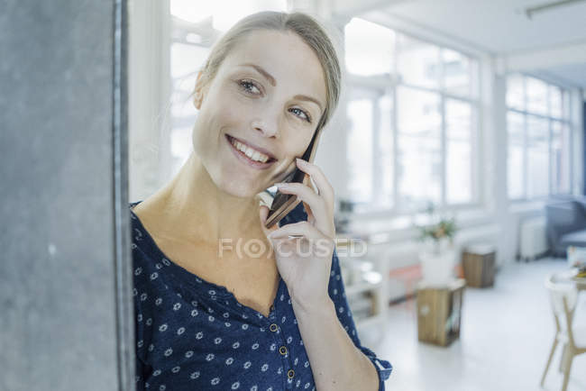 Портрет счастливой молодой женщины по телефону в лофте — стоковое фото
