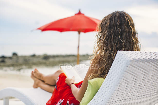 Thailand, Rückansicht einer Frau, die Buch am Strand liest — Stockfoto