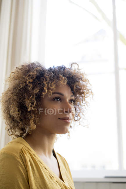 Portrait de jeune femme souriante à la fenêtre — Photo de stock