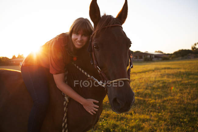 Portrait of smiling woman on horse at sunset — Stock Photo