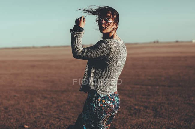 Young woman with windswept hair standing in desert landscape — Stock Photo