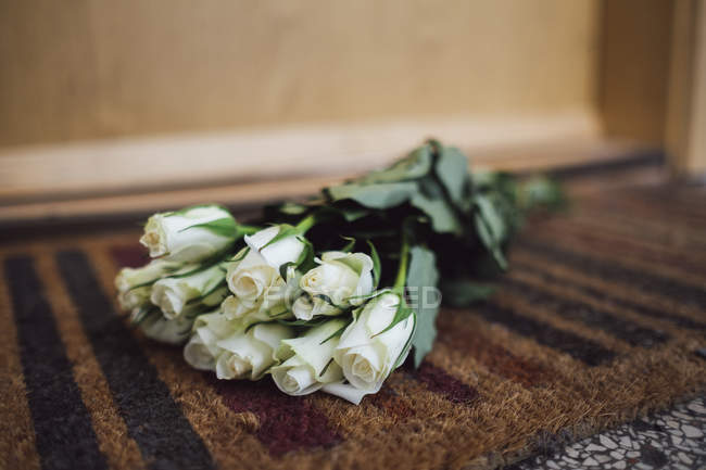 Bando de flores brancas de despedida deitadas no tapete de chão na porta do apartamento do vizinho falecido — Fotografia de Stock