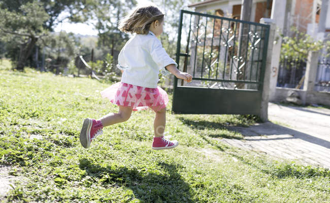 Little girl running on meadow in the garden — Stock Photo