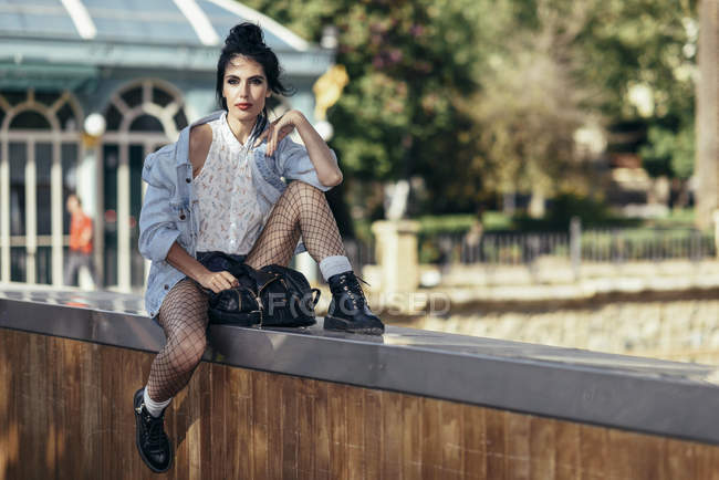 Portrait of fashionable woman sitting on wall — Stock Photo
