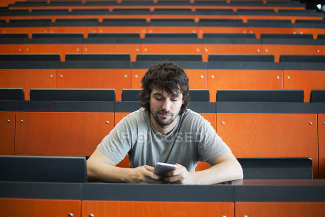 Ritratto di studente in auditorium all'università che guarda il cellulare — Foto stock