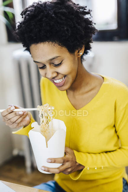 Young african american woman eating Asian noodles for lunch with chopsticks — Stock Photo