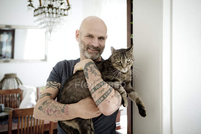 Tatuato uomo portando il suo gatto — Foto stock