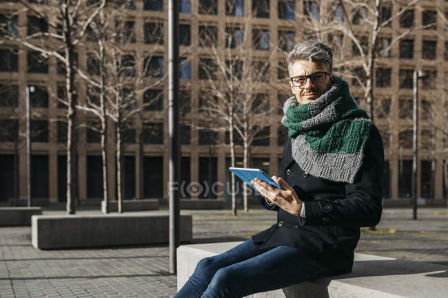 Empresário com tablet sentado no banco da cidade no inverno — Fotografia de Stock
