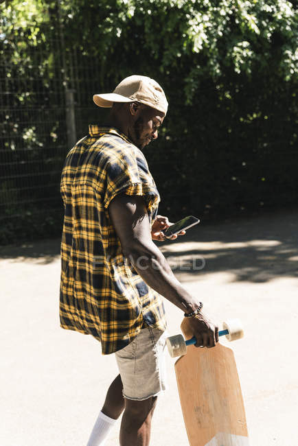 Cooler junger Mann im Skatepark mit Smartphone — Stockfoto
