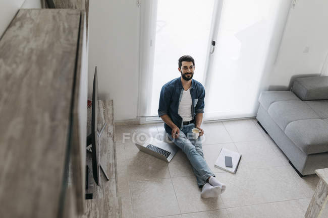 Uomo al lavoro, seduto sul pavimento del soggiorno — Foto stock