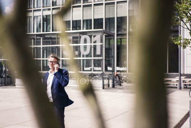 Mature businessman on cell phone outdoors — Stock Photo