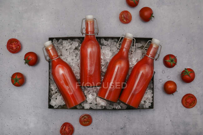 Ice-cooled homemade tomato juice in swing top bottles — Stock Photo