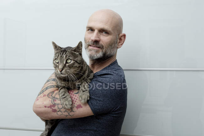 Hombre tatuado llevando a su gato - foto de stock