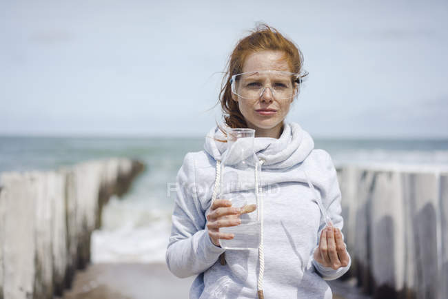 Scientifique avec lunettes de sécurité prélevant des échantillons d'eau à la plage — Photo de stock