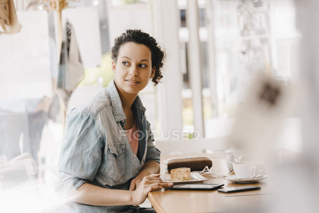 Молода жінка працює в робочому місці і їсть торт. — стокове фото