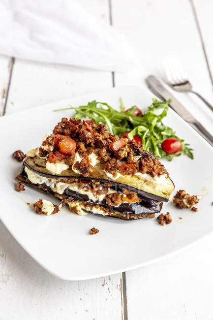 Aubergine lasagne on plate, rucola and tomato, vegetarian — Stock Photo