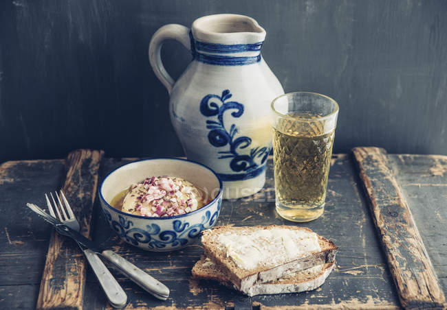 Glass and jar of Hessian cider, bread and bowl of hand cheese — Stock Photo
