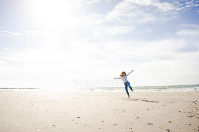 Mujer feliz divirtiéndose en la playa, bailando en la arena - foto de stock