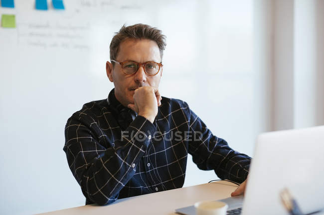 Ritratto di uomo d'affari serio con computer portatile alla scrivania in ufficio — Foto stock