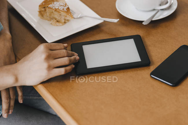 Hand of woman on table with cake and digital tablet — Stock Photo