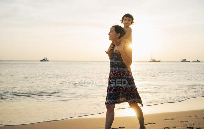 Thaïlande, Krabi, Koh Lanta, Mère avec sa petite fille sur les épaules sur la plage au coucher du soleil — Photo de stock