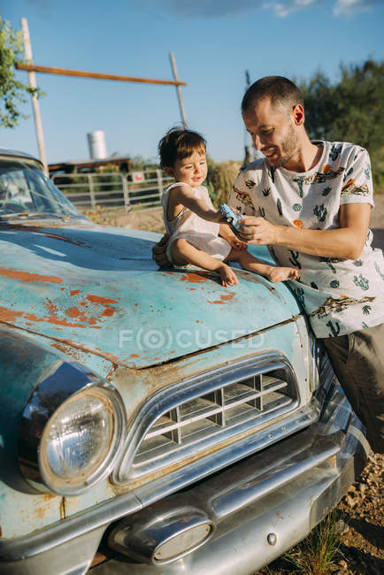 USA, Arizona, Father and baby playing with a reproduction of an old vintage car, at Route 66 — Stock Photo