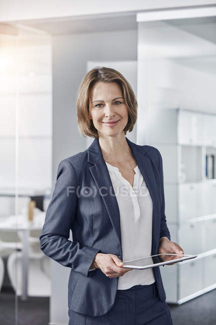 Retrato de una mujer de negocios sonriente sosteniendo la tableta en la oficina - foto de stock