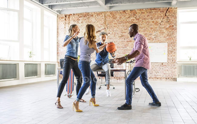 Colleagues playing basketball in office — Stock Photo