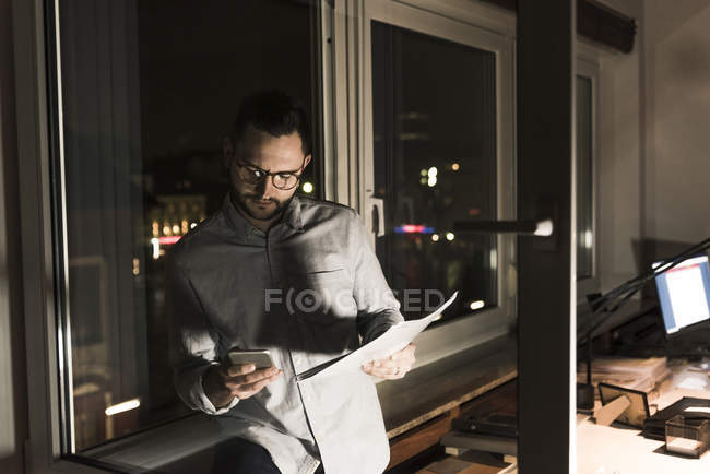 Homme d'affaires au bureau la nuit en utilisant un smartphone — Photo de stock