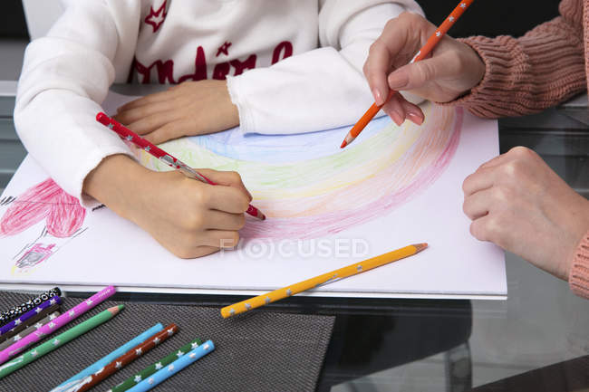 Madre e hija pequeña dibujando un arco iris, vista parcial - foto de stock