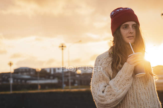 Islanda, giovane donna con caffè per andare al tramonto — Foto stock