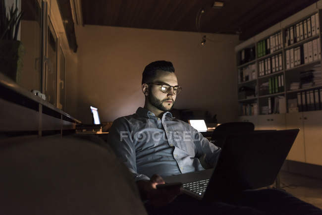 Empresário trabalhando no laptop no escritório à noite — Fotografia de Stock