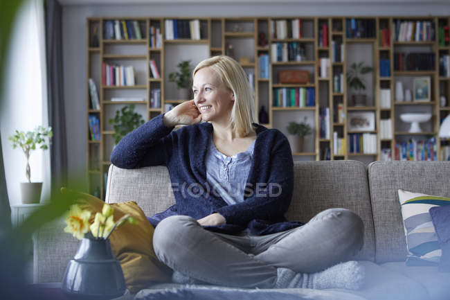 Женщина отдыхает дома, сидит на диване — стоковое фото