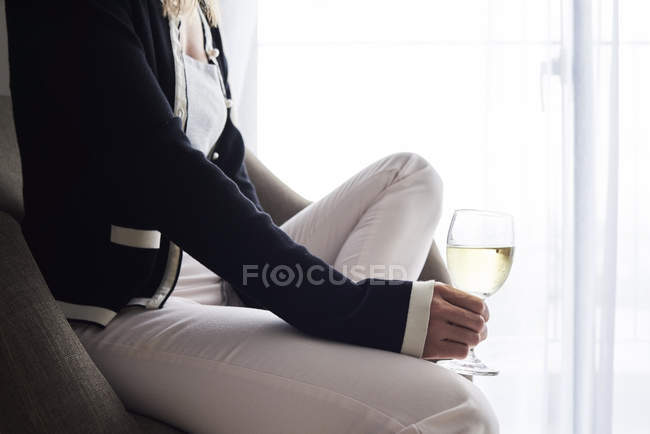 Крупним планом жінка, що має келих вина вдома сидить у кріслі — стокове фото
