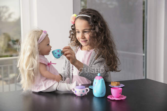 Ritratto di bambina sorridente che gioca con il set di porcellana di bambola e bambola — Foto stock