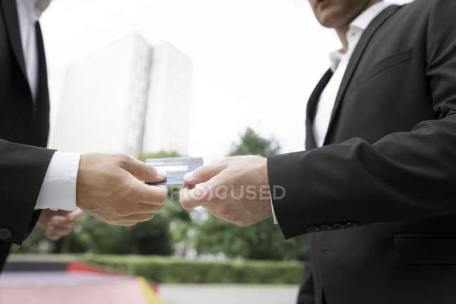 Two businessmen handing over credit card — Stock Photo