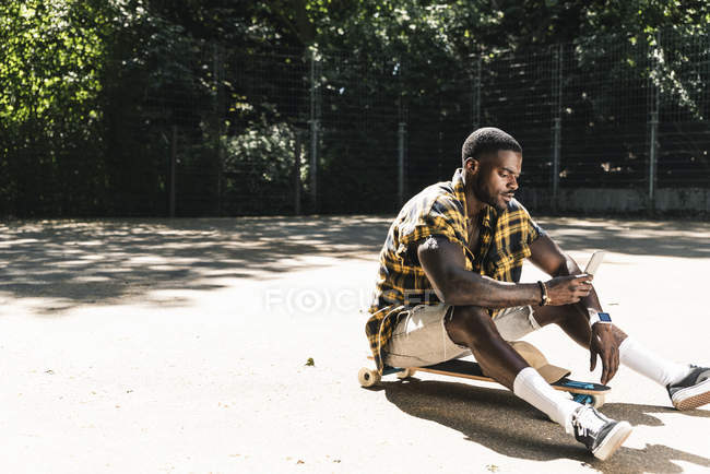 Cooler junger Mann im Skatepark mit Smartphone — Stockfoto