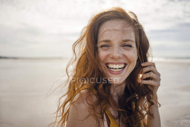 Portrait of a redheaded woman, laughing happily on the beach — Stock Photo