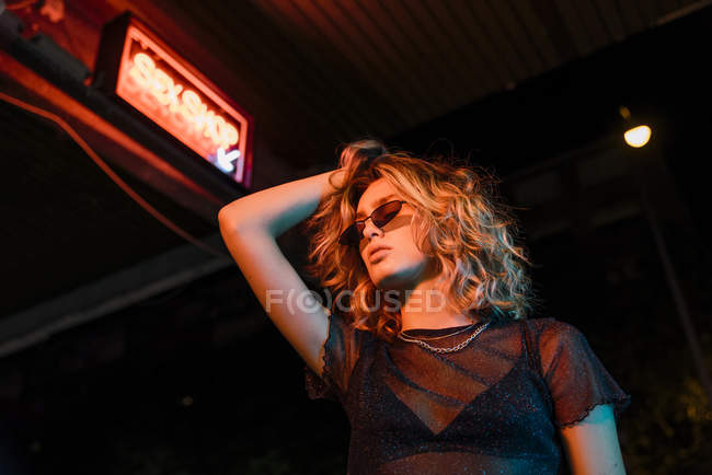 Elegante giovane donna di notte, in piedi di fronte al sex shop — Foto stock