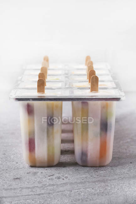 Homemade fruits and yogurt ice lollies on marble — Stock Photo