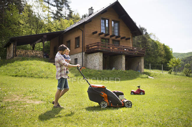 Father with his little son mowing the lawn — Stock Photo