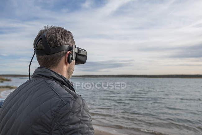 Hombre con gafas VR a orillas del lago - foto de stock