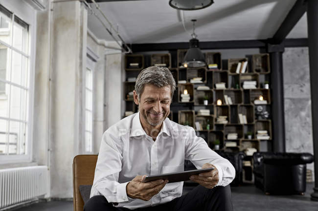 Smiling mature man using digital tablet in loft — Stock Photo