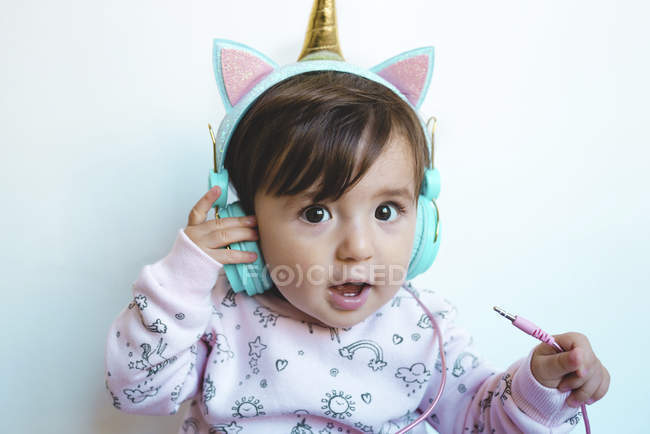 Porträt eines überraschten Mädchens mit Einhorn-Kopfhörern — Stockfoto