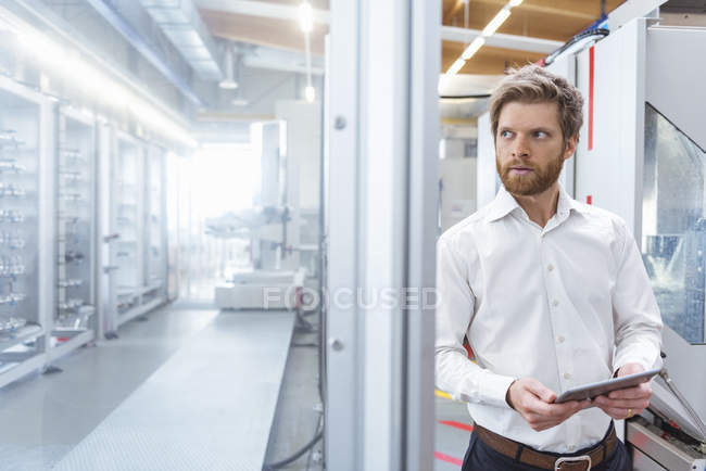 Geschäftsmann mit Tablet schaut Maschine in moderner Fabrik an — Stockfoto