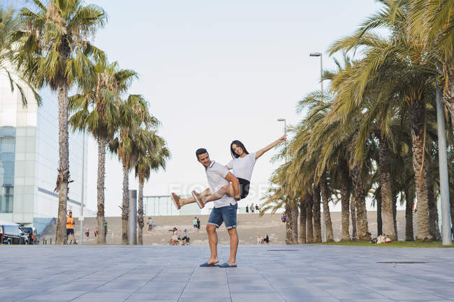 Feliz casal na cidade, homem carregando namorada piggyback — Fotografia de Stock