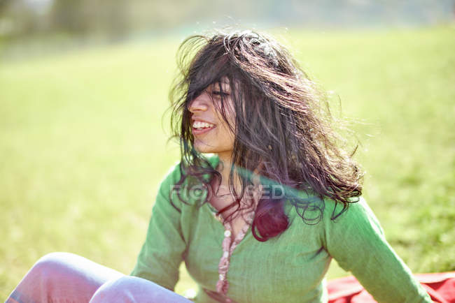 Happy young woman with windswept hair on a meadow — Stock Photo