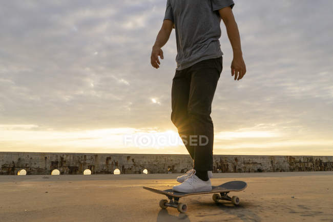 Jeune homme chinois skateboard au lever du soleil près de la plage — Photo de stock